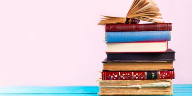 A Stock photo image of a stack of books infront of a light pink background.