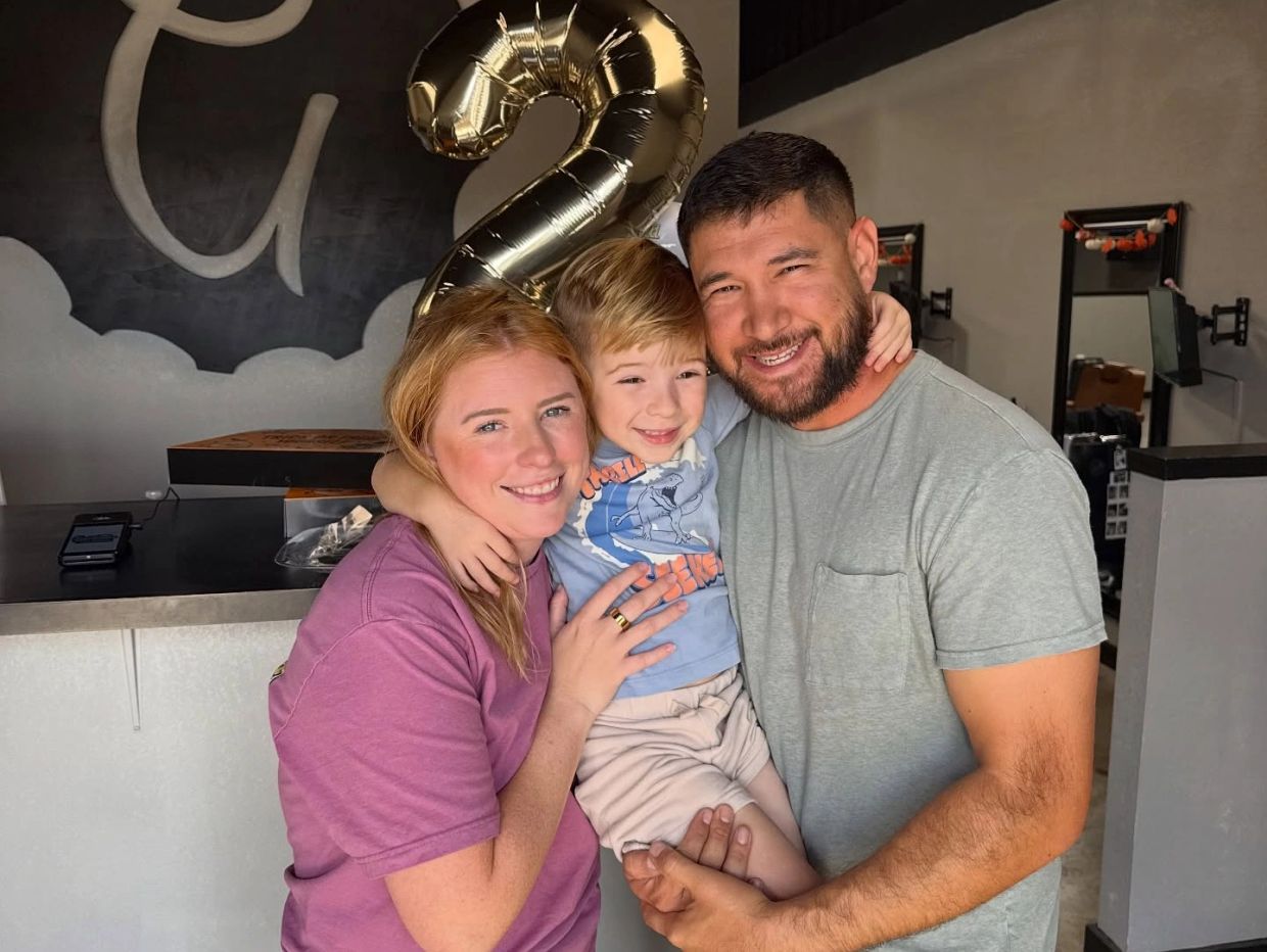A happy family celebrating a child's second birthday with a balloon shaped like the number 2.
