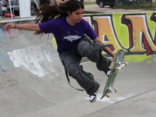 Young woman performing a skateboard trick in a skatepark.