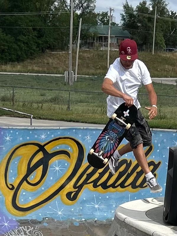 A skateboarder performs a trick mid-air at a colorful skatepark ramp.