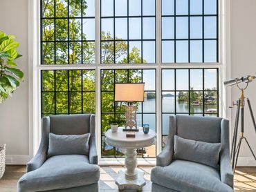 Cozy sitting area with two blue chairs by a large window overlooking a lake.