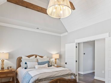 Cozy bedroom with wooden furniture, soft lighting, and a vaulted ceiling with exposed beams.