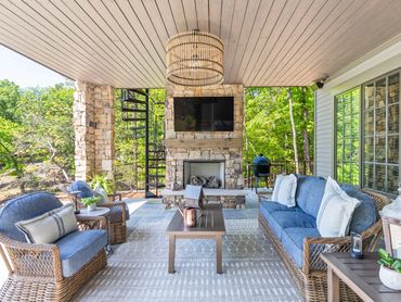 Cozy outdoor patio with wicker furniture and stone fireplace.