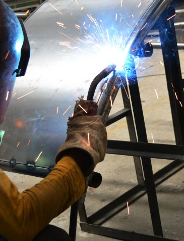 Worker welding metal with sparks flying.