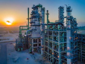 Industrial refinery complex at sunset with tall distillation towers.