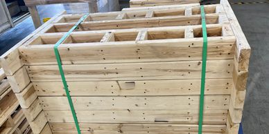 Stacked wooden pallets secured with green straps in a warehouse.