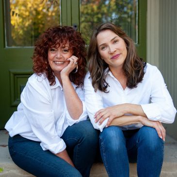 Two women sitting together outside, smiling.