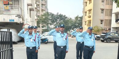 Six security guards saluting while standing in a parking area.