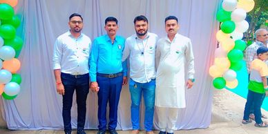 Four men posing in front of a balloon-decorated backdrop with white curtains.