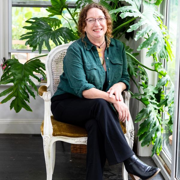 woman sitting on chair with pot plant benhind