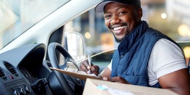 Delivery man smiling inside a vehicle with clipboard.