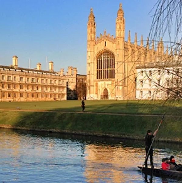 A person punting on the river by a historic building.
