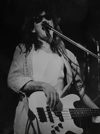 Black and white photo of a musician playing bass and singing.