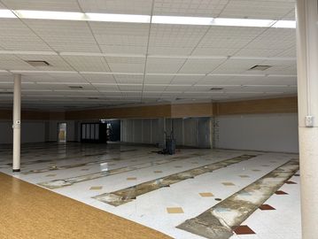 Empty, partially renovated commercial space with tiled floors and ceiling panels.