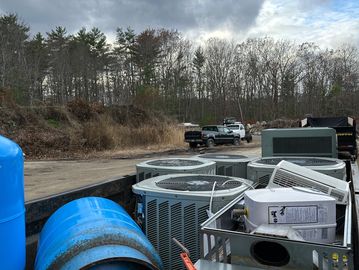 Truck bed loaded with HVAC equipment and tools under a cloudy sky.