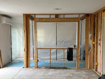Room under renovation with exposed wooden framing and plastic sheeting.