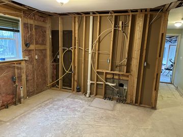 Room under renovation with exposed wall studs and plumbing.
