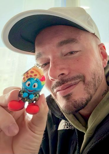 J Balvin holds the Slimesen prototype, supporting artist Mohamed Ali . The figure mimics Balvin's pe