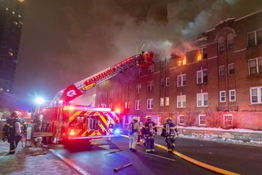 Fire engine with a bucket squirting water on a fire in an apartment window