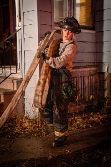 Blonde firefihghter carrying hose
