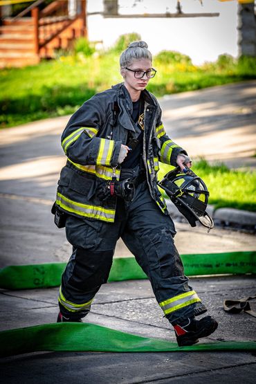 Female Fire fighter walking with her black helmet in hand