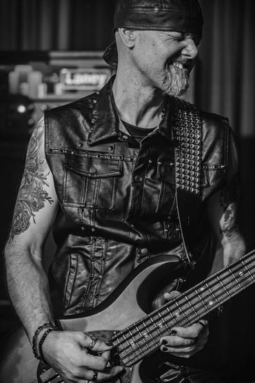 Rock musician passionately playing bass guitar on stage.