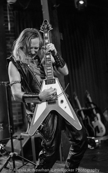 Rock musician passionately playing a blue and white electric guitar on stage.