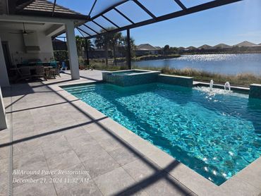Luxury poolside patio with lake view and outdoor kitchen.