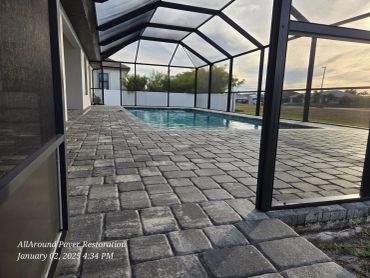 Paved patio area surrounding a screened-in pool enclosure.
