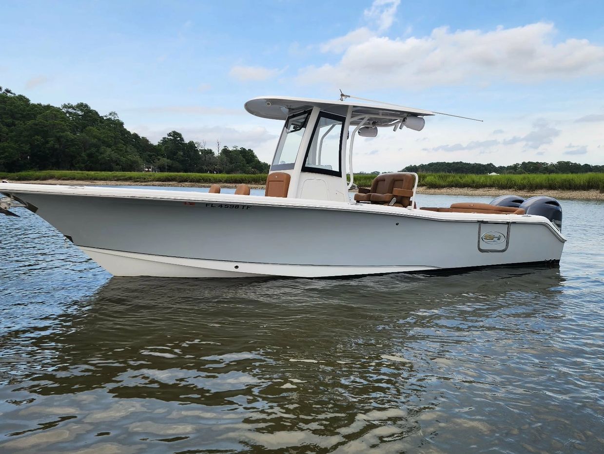A white motorboat with brown seats floating on water.