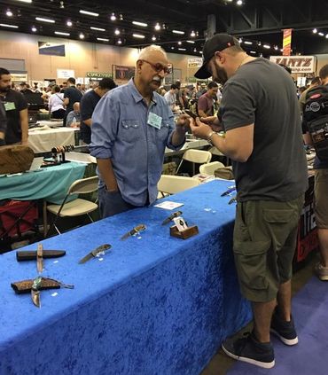 Robert Champion at Blade Show showing customer a custom knife
