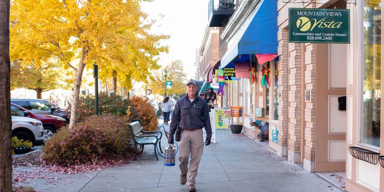 Photo of downtown Hendersonville in Henderson county and Noble Pest technician walking on the sidewa