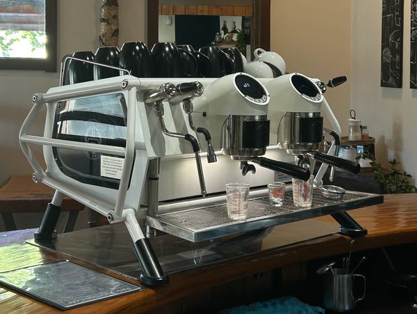 Modern white espresso machine on a wooden counter.