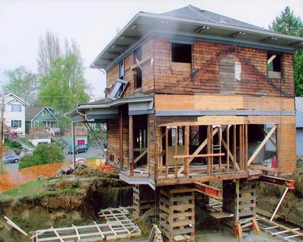 Two story house sitting on lifting beams and crib piles to build a new foundation