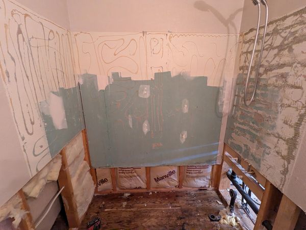 Bathroom mid-renovation with exposed insulation and pipes.