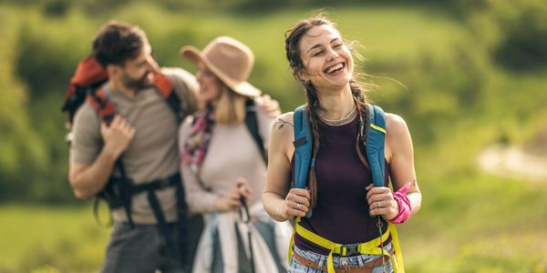 Happy woman hiking with friends in a green outdoor setting.