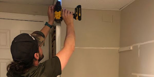 Man using a drill to work near a ceiling.