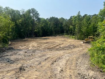 Cleared land with bulldozer and trees surrounding the area.