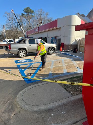 Worker painting blue handicap parking symbol in front of Circle K store.