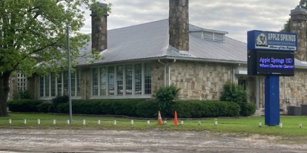 Stone building with Apple Springs ISD signboard.