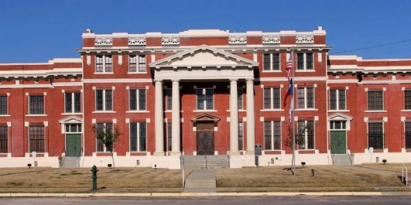 Historic red brick building with columns and green doors.