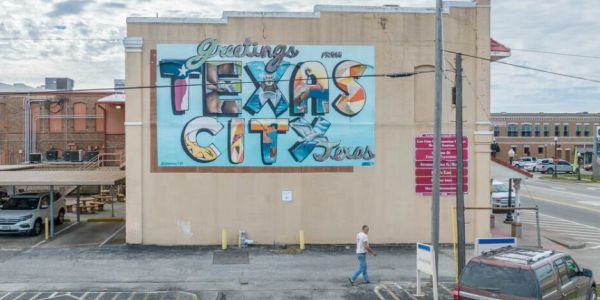 Mural reading 'Greetings from Texas City Texas' on building.