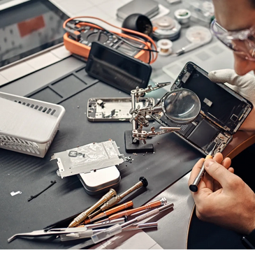 Technician repairing a smartphone with tools and magnifying glass.