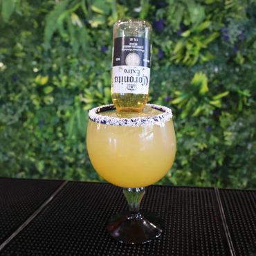 Cocktail with an upside-down Corona bottle and a salt-rimmed glass.