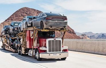 A trailer truck with 8 various cars being transported on it