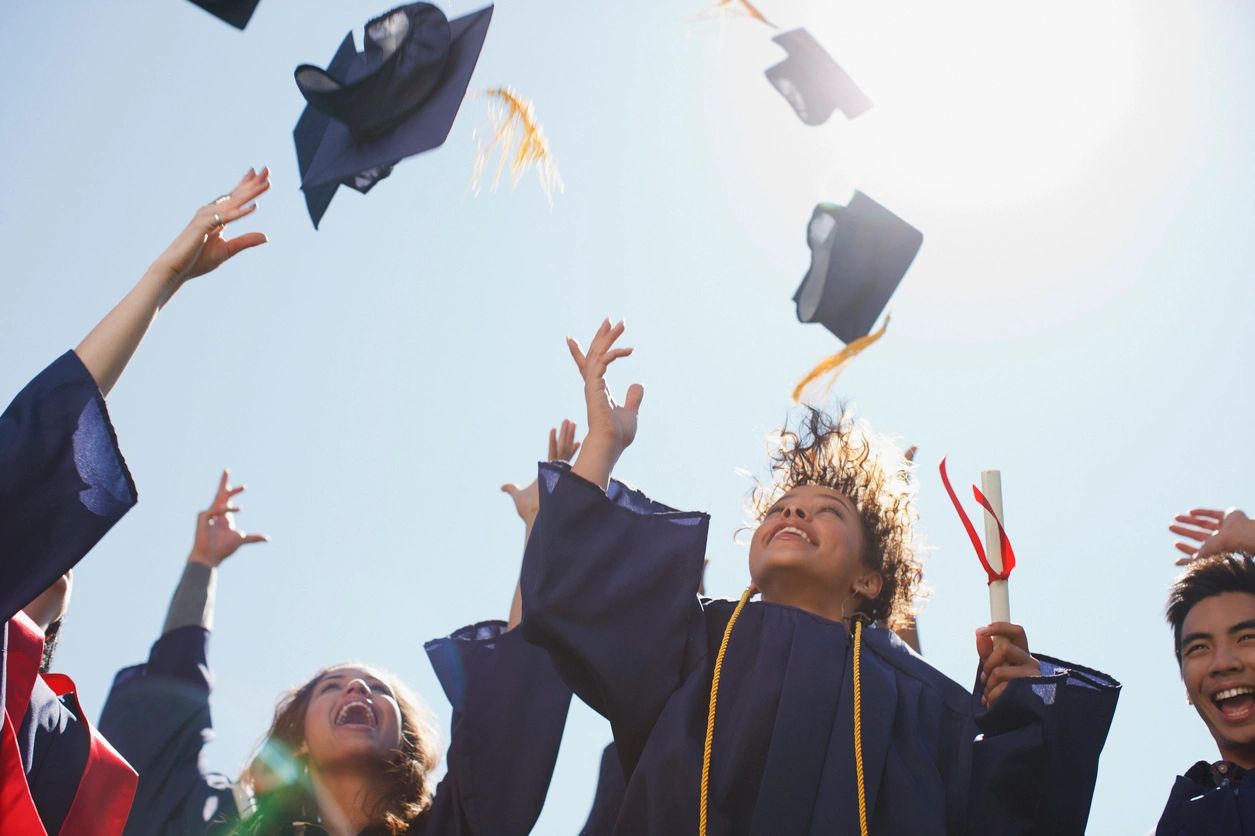 Graduates tossing caps in the air, embodying success akin to mastering OIWA Auction University