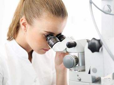 Female scientist looking down a microscope
