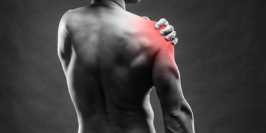 man's back holding his right shoulder in pain