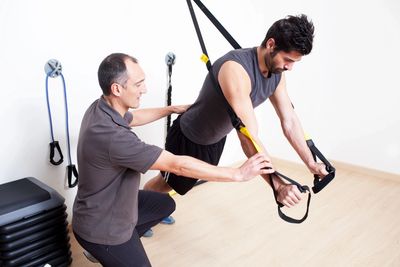 Physical therapist exercising a client with TRX exercise straps