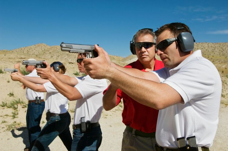 People shooting handguns at an outdoor range.